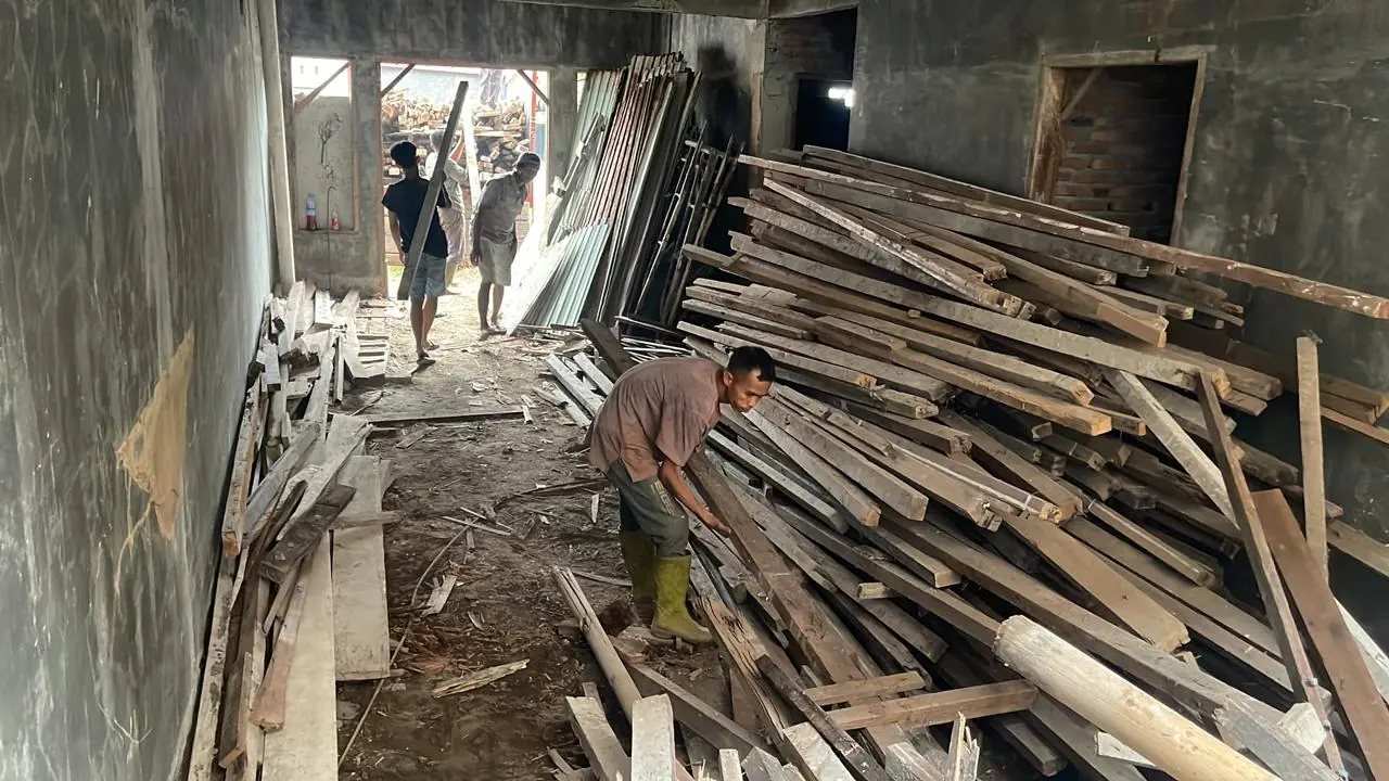 Pekerja memilah kayu hasil bongkaran di dalam bangunan yang sedang dibongkar