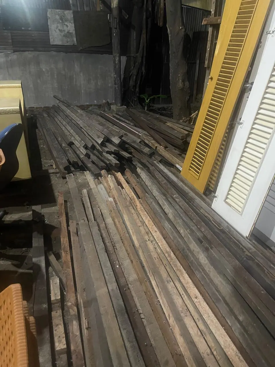 Balok kayu dan daun pintu bekas tersusun di gudang