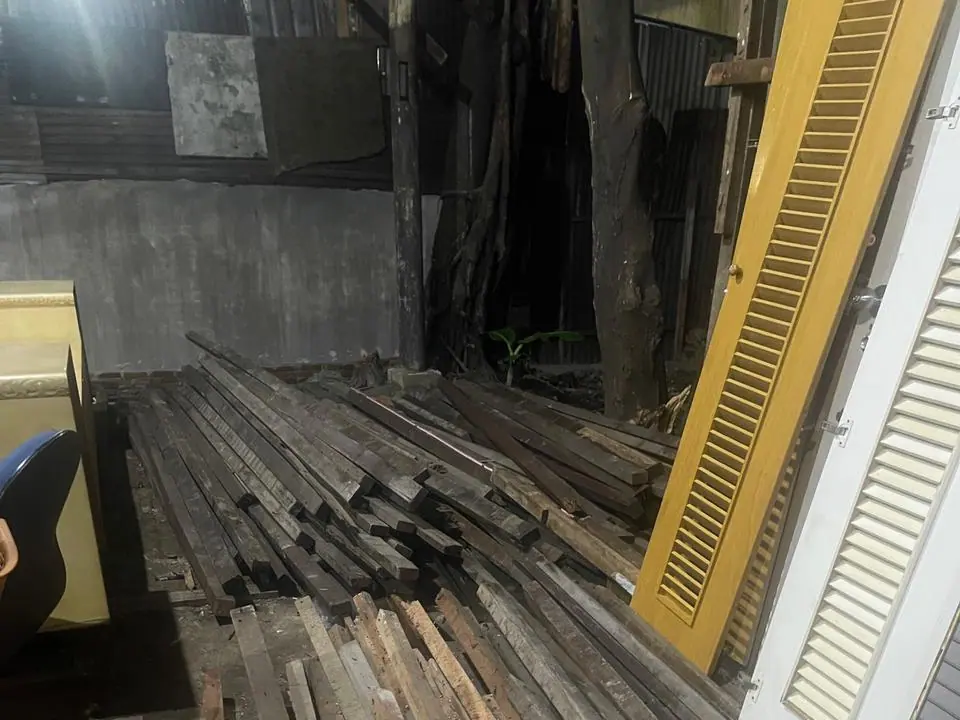 Balok kayu dan daun pintu bekas tersusun di gudang