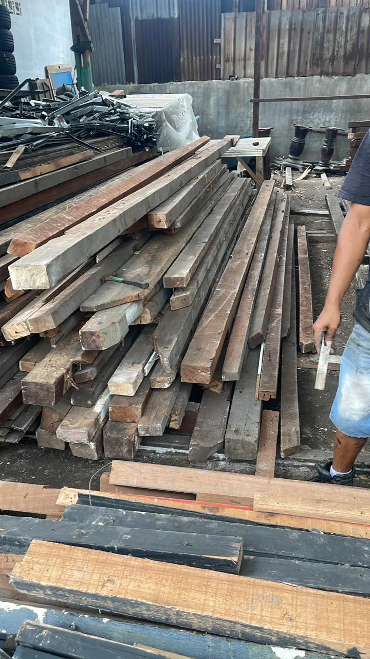 Pekerja memeriksa balok kayu hasil bongkaran